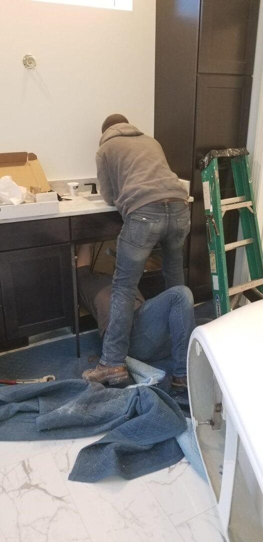 Two technicians working on sink drain pipes